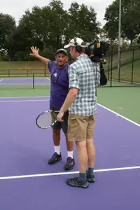 Women's tennis coach Dave Borelli talks with the camera crew during filming for the television series.