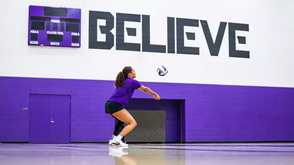 Jalyn Gibson taking passing reps with a wall that reads "Believe" in the background