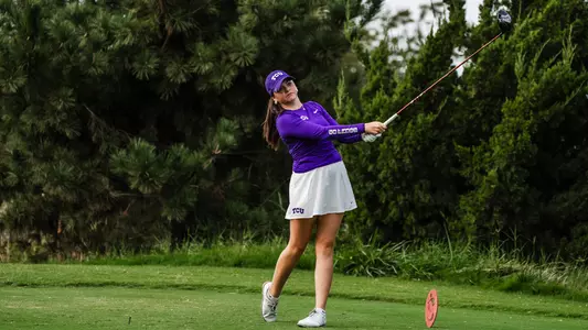 Gracie McGovern holds her follow through on a tee shot wearing a purple long-sleeve shirt