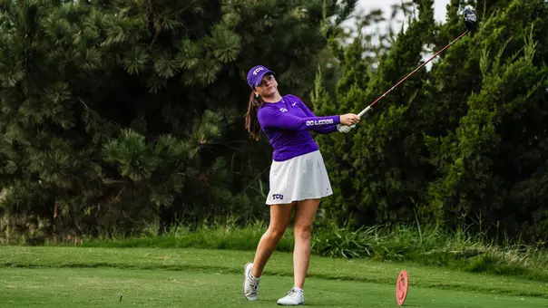 Gracie McGovern holds her follow through on a tee shot wearing a purple long-sleeve shirt