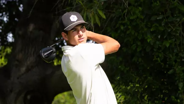 Sam Udovich swings a golf club and stares into the sun with a follow through
