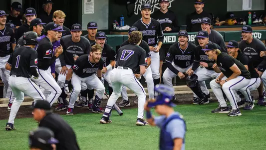 Rob Liddington celebrates a home run with his team in front of the dugout.