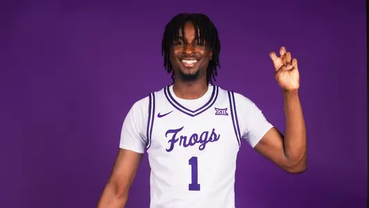 Luke Bamgboye poses in a white uniform against a purple background.