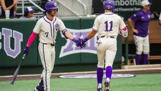 Cole Cramer and Colton Griffin slap hands at home plate.