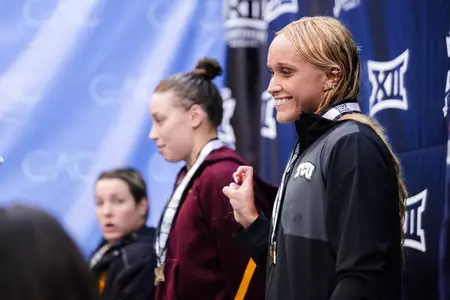 Molly Cullen holding up the Frog sign after medaling at the Big 12 Championships