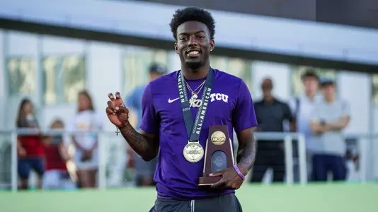 TCU's Jayden Douglas stands on the podium holding a trophy after finishing sixth in the 400m hurdles