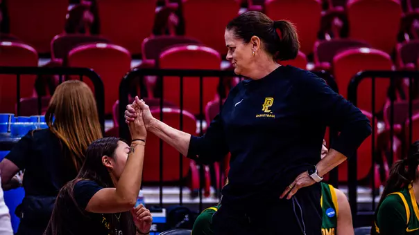 Charity Elliott high fives a player on the bench during a game