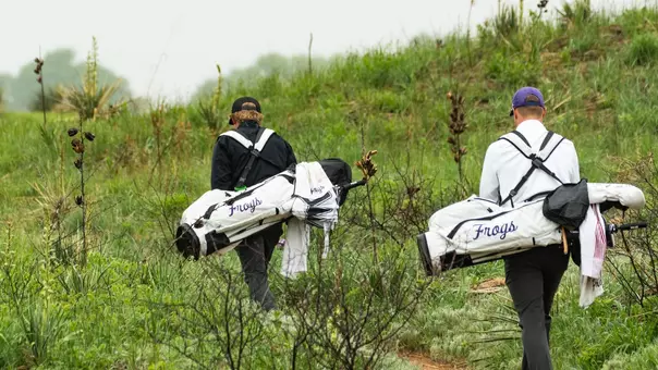 Charlie Wylie and Lewis Wright walk to their next hole carrying white golf bags.