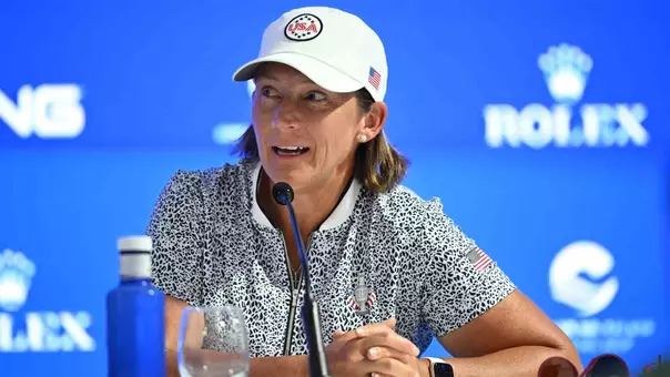 Angela Stanford addresses the media wearing a white U.S. Solheim Cup hat