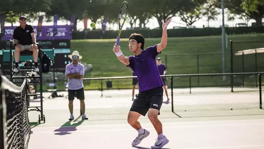 Duncan Chan prepares to connect on a volley at the net while wearing a purple shirt