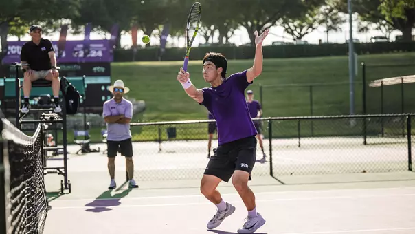 Duncan Chan prepares to connect on a volley at the net while wearing a purple shirt