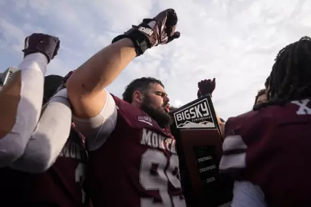 Alex Gubner #99 of the Montana Grizzlies celebrates with the Big Sky Conference Trophy after the game against the Montana State Bobcats at Washington-Grizzly Stadium in Missoula, Montana on November 18, 2023.