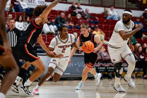 Chase Henderson charges past defenders during the basketball game between the Montana Grizzlies and the University of Denver Pioneers in Dahlberg Arena, in Missoula MT, on October 26, 2025.