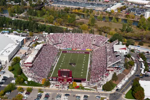 An aerial shot of a packed Washington Grizzly stadium on Griz game day with the Clark Fork River flowing by.