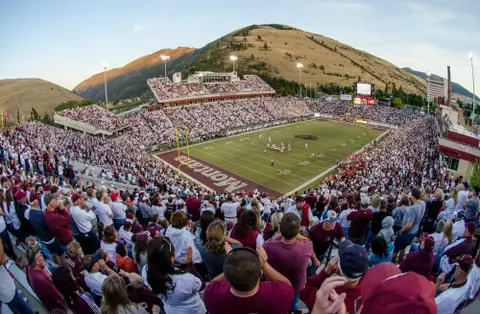 A wide angle shot of the Griz football team taking on an opponent inside Washington Grizzly Stadium under the lights.