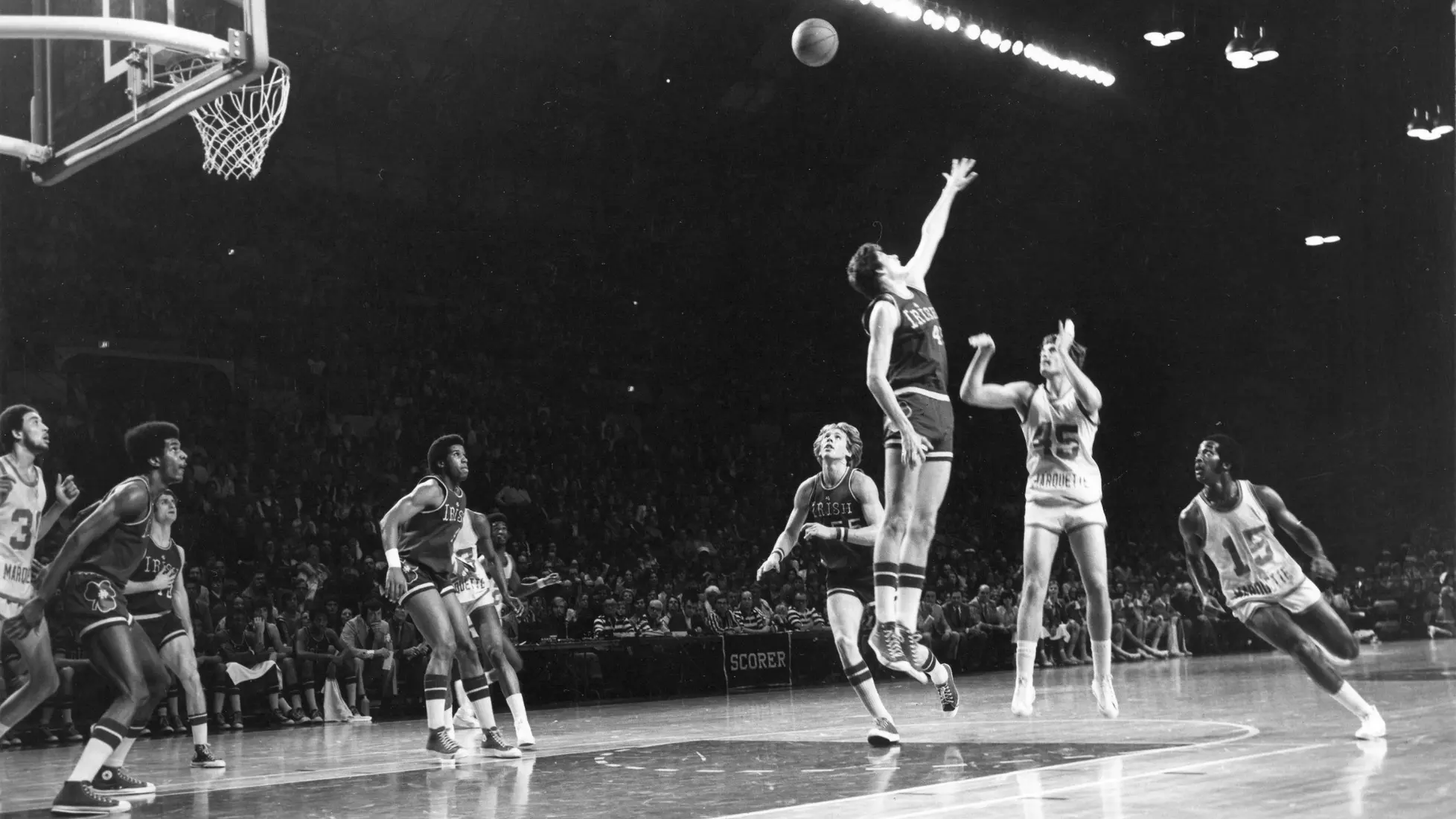 Marquette basketball player Jerry Homan takes a shot in a basketball game against Notre Dame. Alfred (Butch) Lee and Bo Ellis are going in for a rebound.
Jerry Homan, Butch Lee, Bo Ellis, Men's Basketball, Athletes