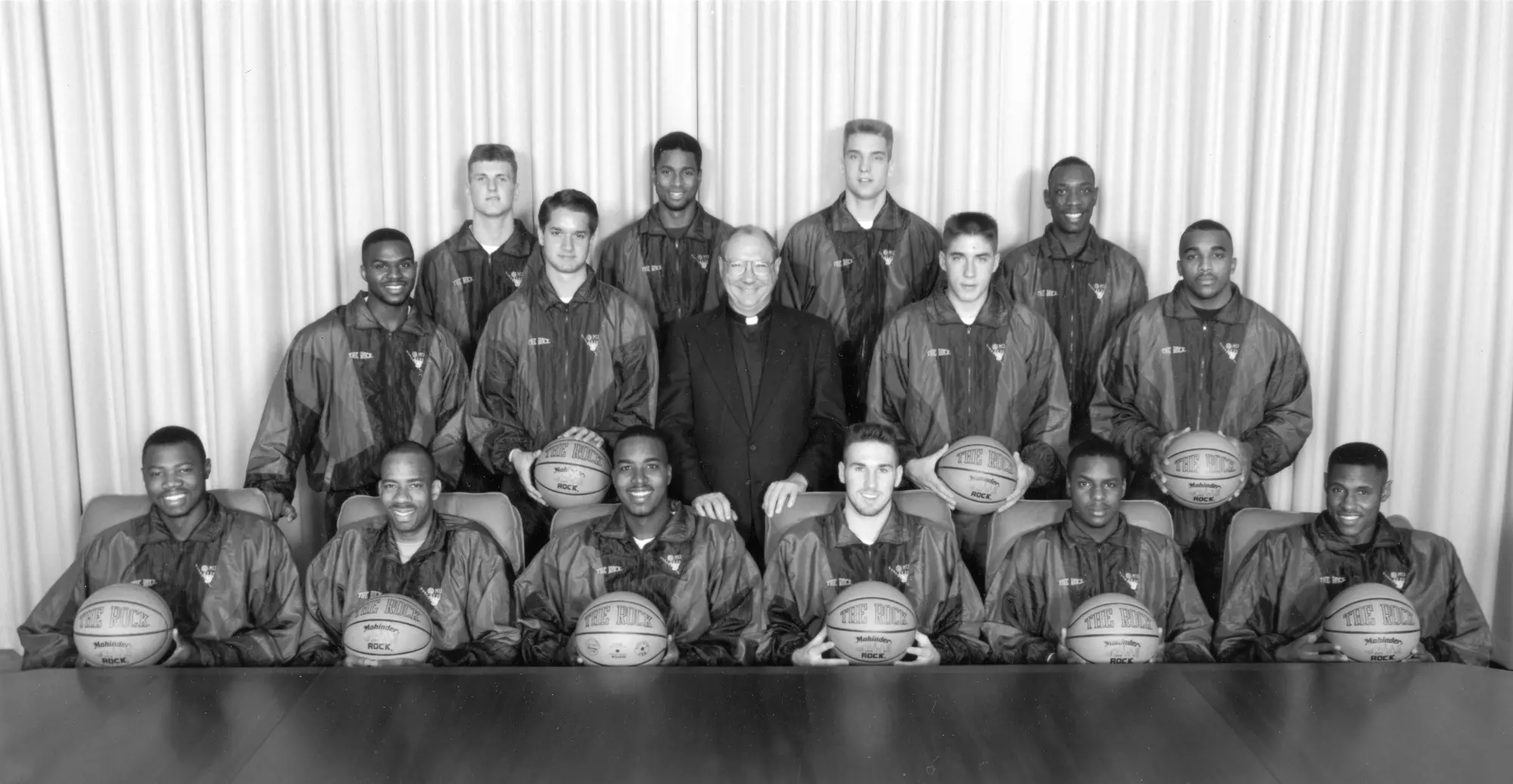 The Marquette men's basketball team poses with Marquette University President Rev. Albert J. DiUlio, S.J., 1993. Members of the team that year included Roney Eford, Damon Key, Jim McIlvaine, Tony Miller, Robb Logterman, Amal McCaskill, Anthony Pieper, Faisal Abraham, Abel Joseph, Carl Hren, Shane Littles, Joel Pogodzinski, William Gates, Chris Crawford, and Dwaine Streater.
