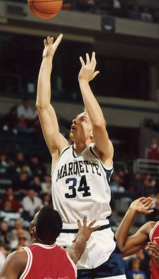 Marquette basketball player Jim McIlvaine jumps to shoot the ball over defenders, 1993-1994.