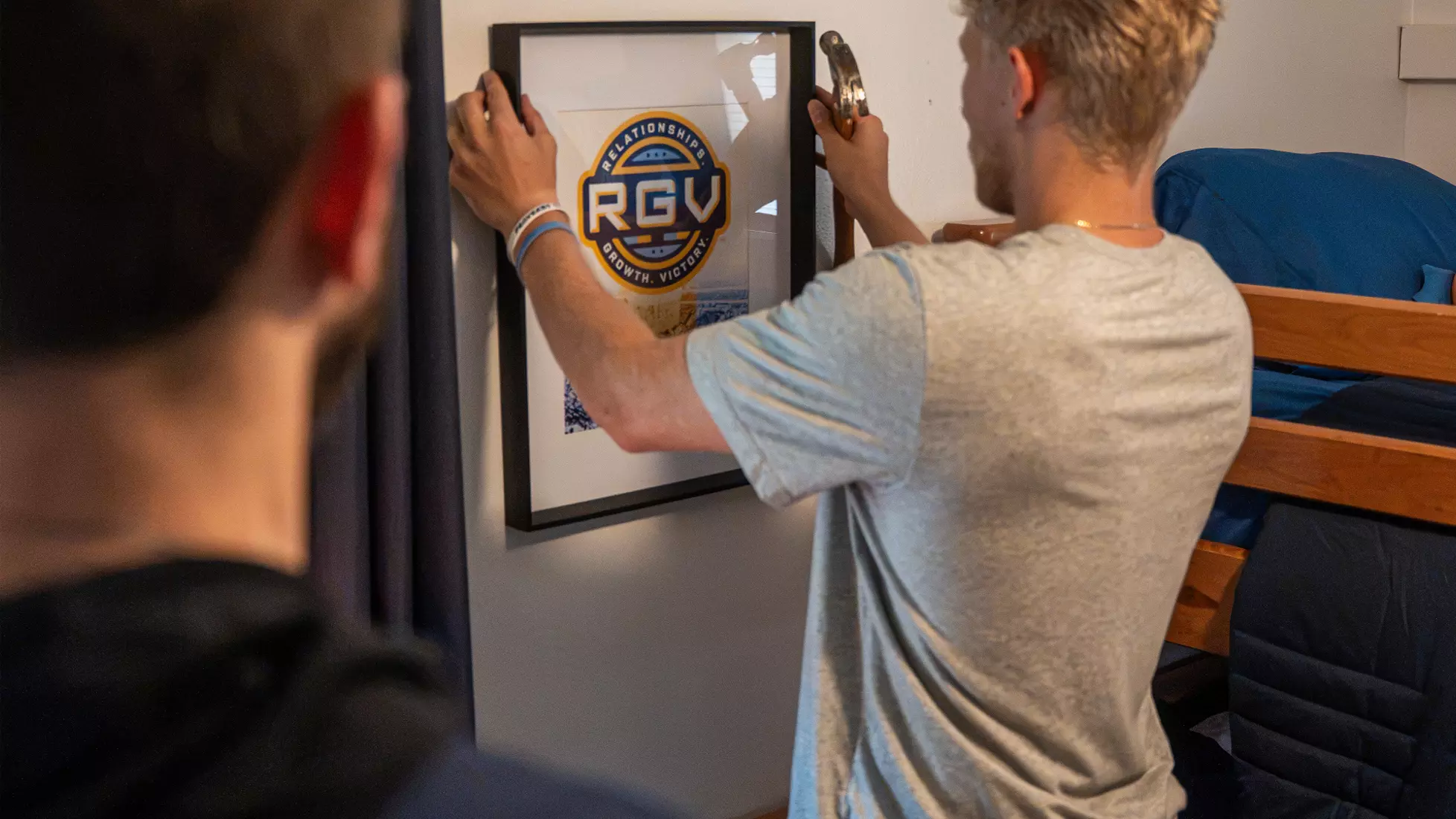 Jack Anderson adds picture frame to wall in a bedroom in the home