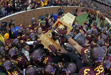 Minnesota players hold the Governor's Victory Bell trophy after the game for the first time since 2004.