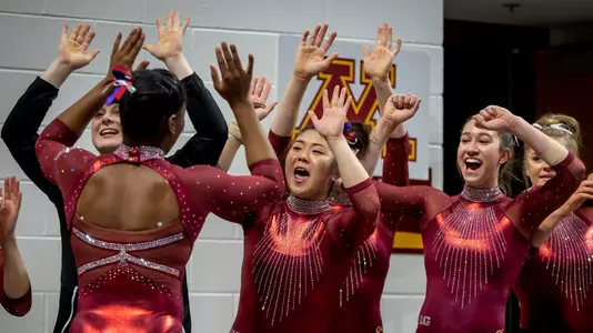 Paige Williams's teammates react to her performance on the floor.