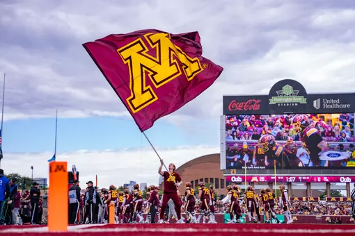 A cheerleader waves a M branded flag at a football game in 2025.