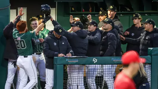 Mustang players in the dugout greet Jake Steels after he scored against Fresno State last week. Cal Poly swept the midweek season series against the Bulldogs.
