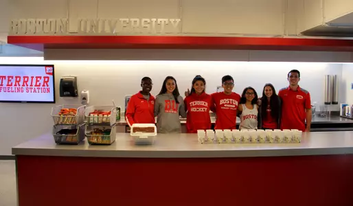 Several student-athletes and Sargent College nutrition majors pose for a group photo behind the counter inside the Terrier Fueling Station.