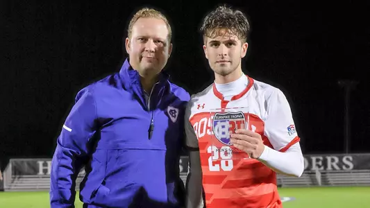 John Siracuse poses for a photo holding the 2018 Turnpike Trophy MVP award with the Holy Cross athletic director.