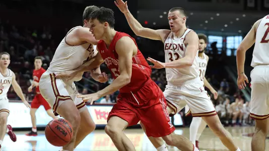 Max Mahoney drives to the hoop at Elon while surrounded by defenders.