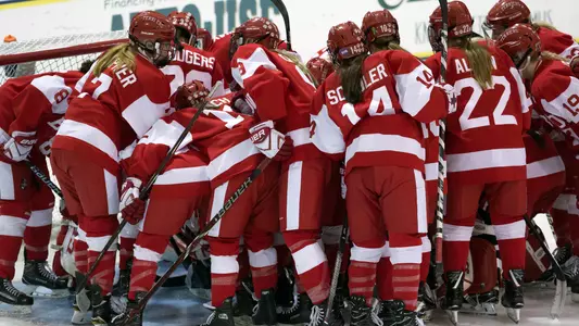 Women's hockey team in a circle around goalie