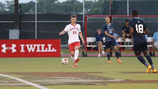 Satchel Cortet centers a pass at midfield with two URI defenders approaching