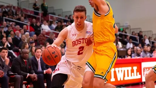 Tyler Scanlon dribbles the ball toward the hoop against a Vermont defender.