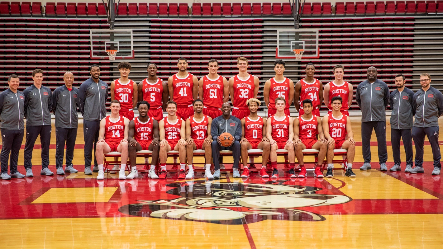 The 2019-20 Boston University men's basketball team is lined up for a team photo with the head coach and eight players sitting in front and eight players plus seven staff members standing in the second row.