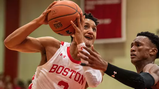 Alex Vilarino goes up in the air for a shot attempt with a Northeastern player guarding him.