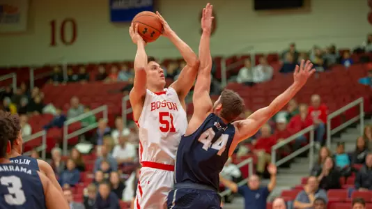 Max Mahoney goes for a jump shot with a New Hampshire player putting a hand in his face.