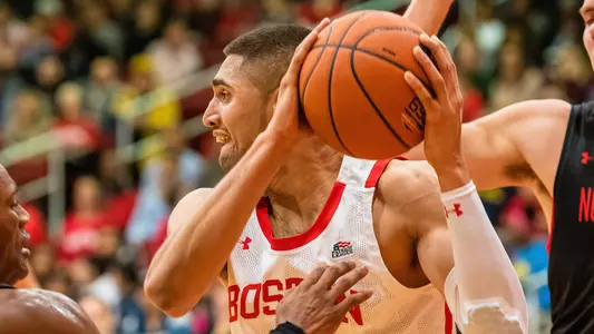 Sukhmail Mathon raises the ball high looking to make a pass while defended in front and behind by Northeastern players.