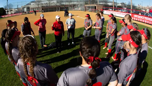 BU Softball team huddle with Coach Waters providing instruction.