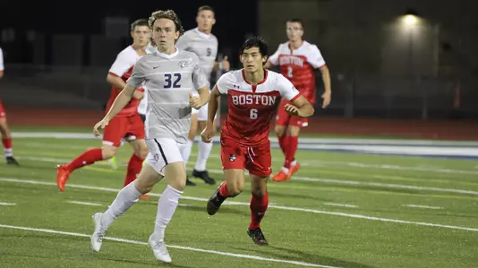 Myles Dycaico runs alongside a UNH defender battling for position for the soccer ball.