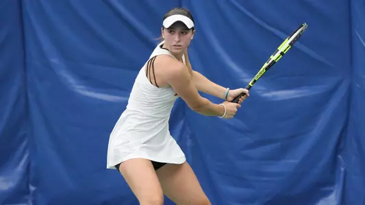 Erica Di Battista gets in position for a backhand shot holding the racquet with two hands.