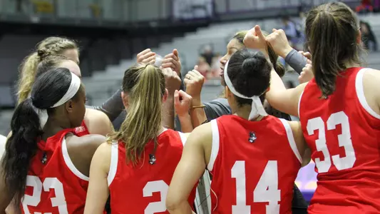 Women's basketball team members huddling during a timeout