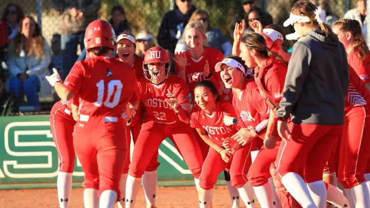 The Boston University softball team gathers around home plate to greet Aliya Huerta-Leipner following a two-run homer at Stetson.