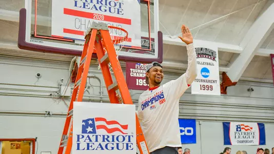 Daman Tate waves to the crowd while standing on the ladder under a hoop at the 2020 Patriot League men's basketball championship postgame celebration.