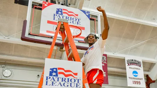 Walter Whyte waves to the crowd while standing on the ladder under a hoop at the 2020 Patriot League men's basketball championship postgame celebration.