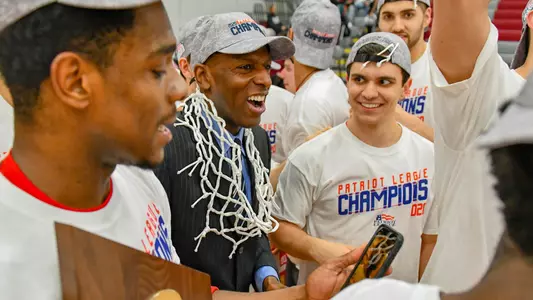 Head coach Joe Jones wears the net around his nick while surrounded by several players celebrating the 2020 Patriot League championship victory.