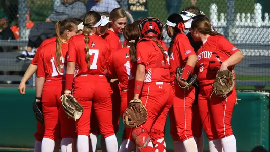The Boston University softball team gathers together in a huddle.