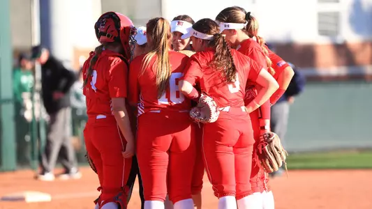 Softball defense and pitcher huddle up in the circle.
