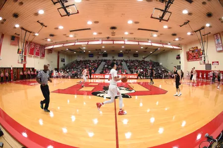 Wide angle view of Case Gym from the midpoint line. A Terrier is dribbling the ball up the court.