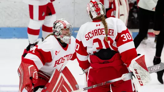 A smiling Kate Stuart gets ready to hug Corinne Schroeder on the ice after a Terrier victory