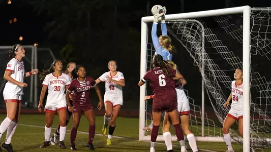 Celia Braun jumps high to catch a corner kick ball up in the air with other players looking on.